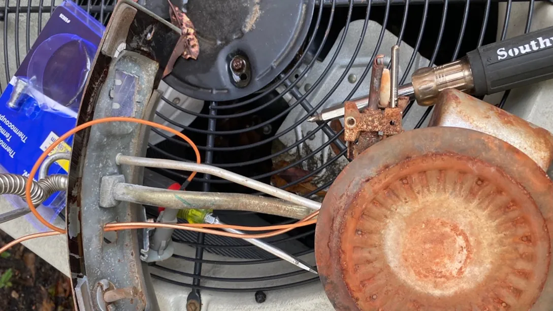 Inside an outdoor AC condenser with the top off, showing the fan motor, copper lines and wiring