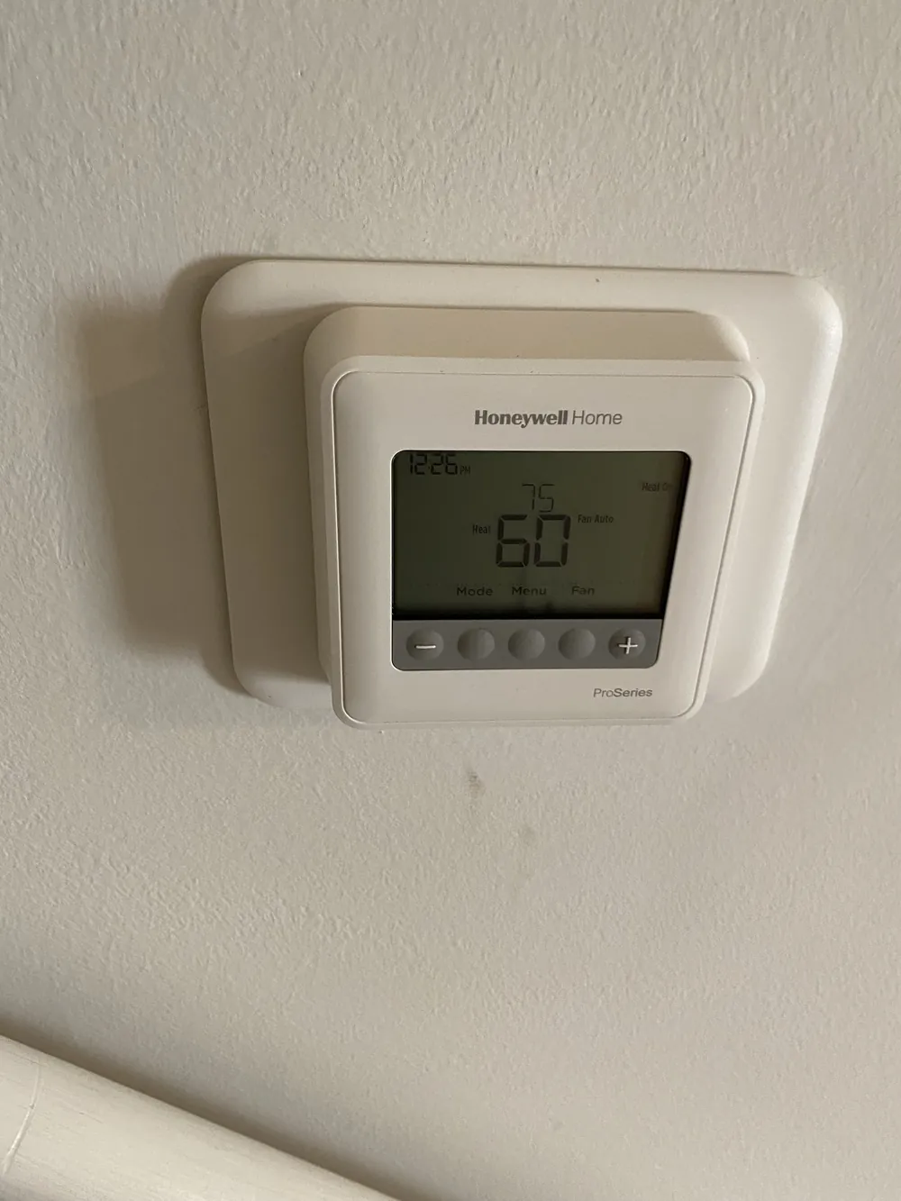 A white Honeywell digital thermostat on a light wall