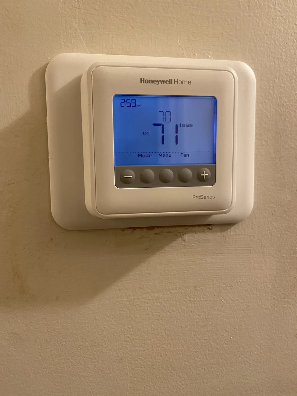 A Honeywell thermostat with its blue display lit