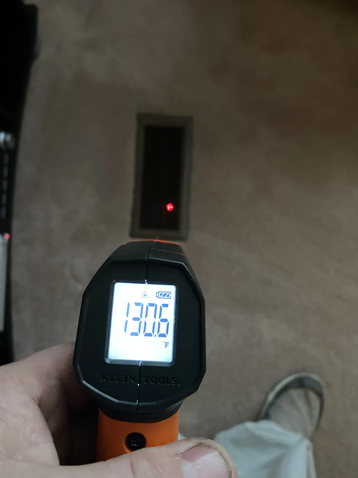 An infrared thermometer aimed at a floor register reading 130.6 degrees Fahrenheit